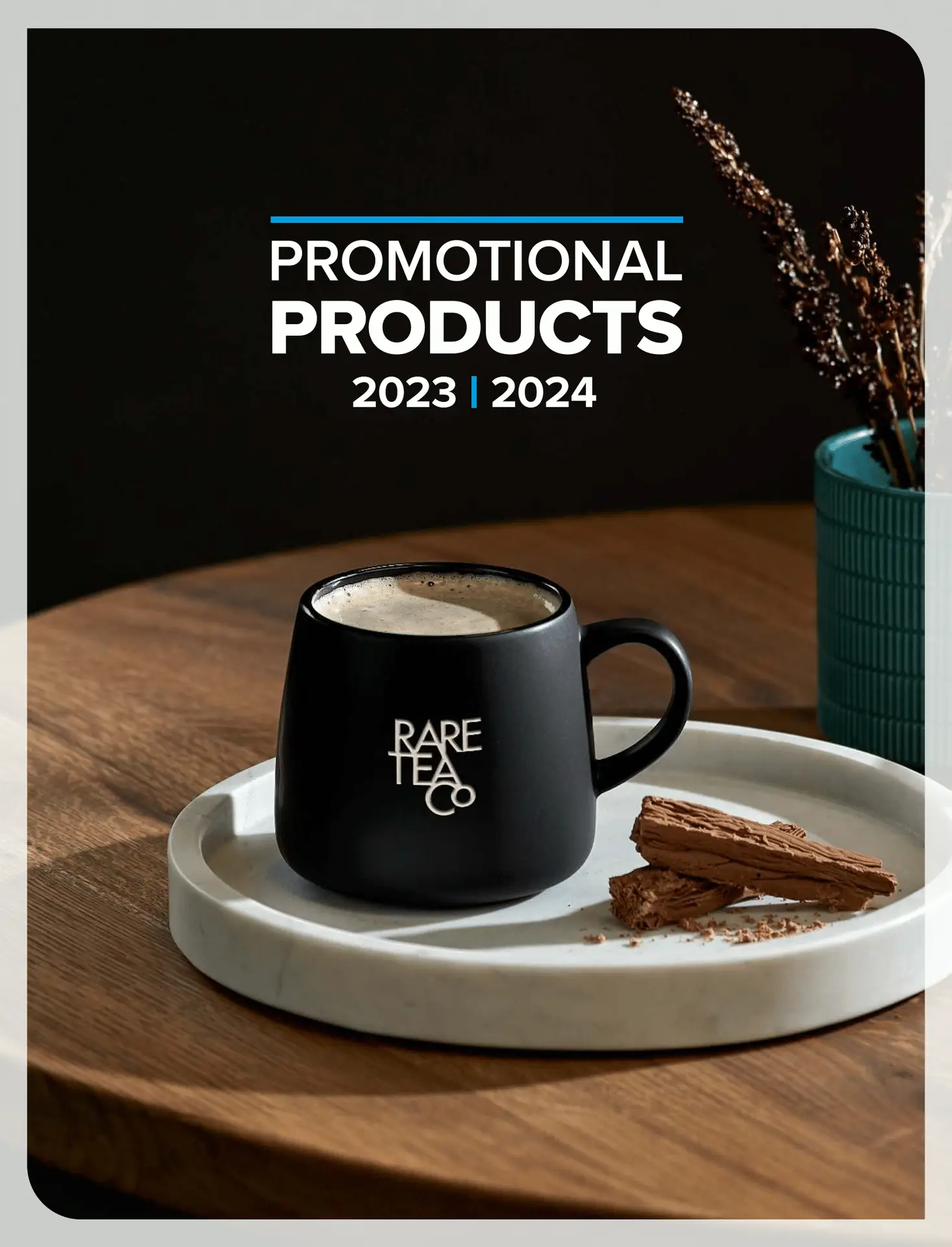A black mug with the "Rare Tea Co" logo sits on a white marble tray, filled with a warm beverage. The mug is accompanied by chocolate pieces on the tray and a teal vase with dried flowers in the background. The image is a catalogue cover for promotional products for the 2023-2024 season. This image showcases Mafloza's corporate wear, gifts, and clothing solutions in South Africa, highlighting the high-quality and stylish promotional items they offer.