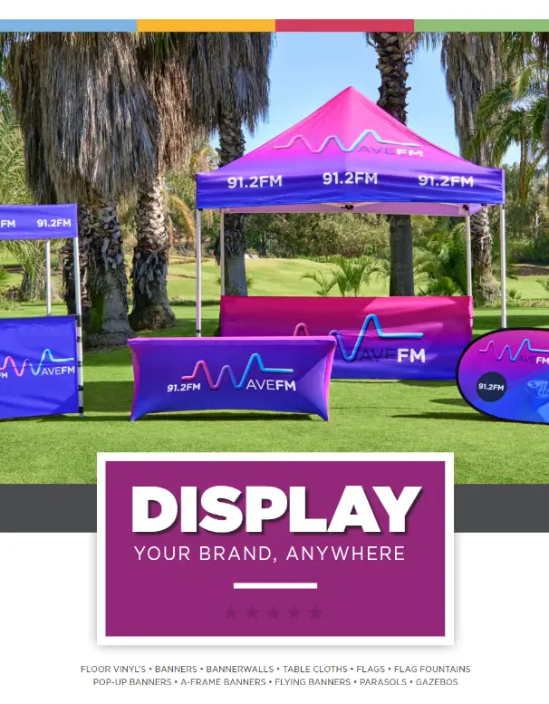 A promotional display setup with a large tent and various banners, all featuring the "Wave FM 91.2FM" logo. The display is set up outdoors on a grassy field, showcasing the versatility of Mafloza's promotional display solutions in South Africa. This image highlights the company's ability to create impactful and eye-catching displays for events and promotions.